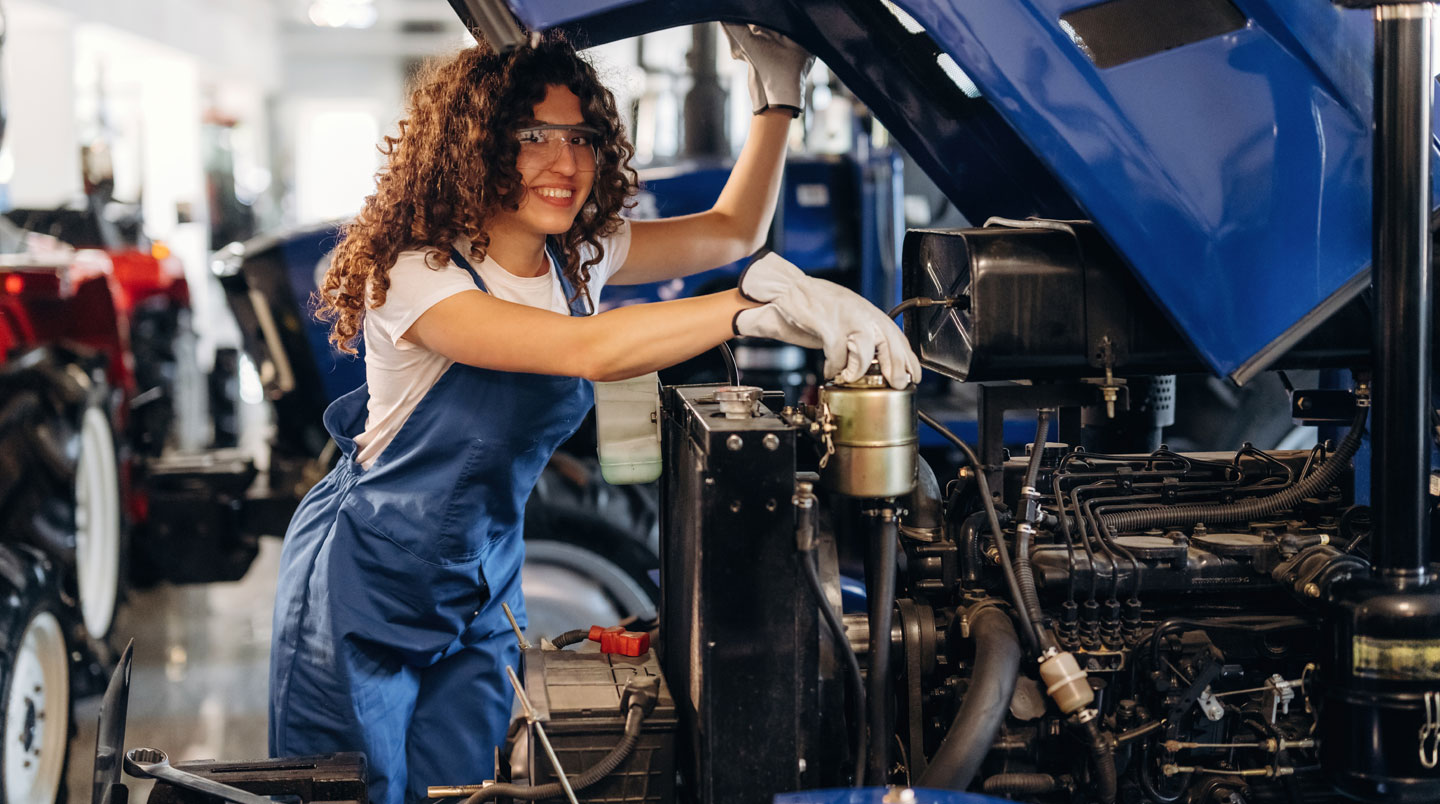 Inspection du système hydraulique d'un tracteur agricole par un technicien vérifiant les distributeurs et vérins de relevage