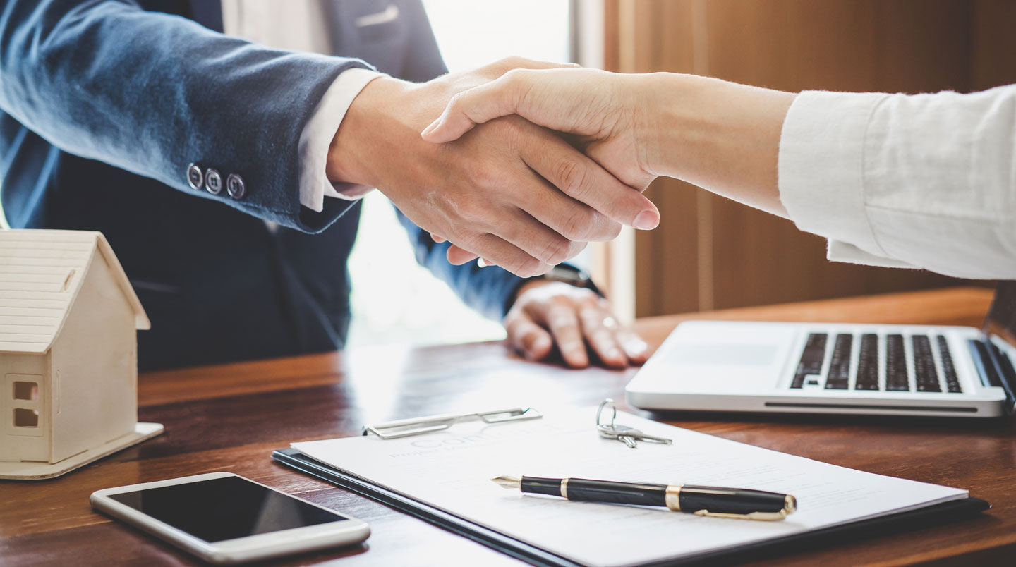 Couple québécois en train de comparer deux contrats d'assurance sur une table de cuisine lumineuse