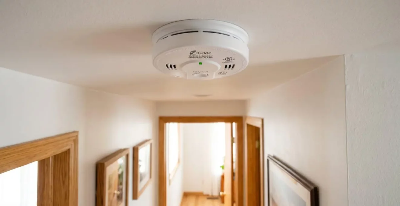 Détecteur de fumée moderne installé au plafond d'un couloir résidentiel québécois bien éclairé