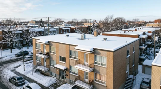 Bâtiment commercial à toit plat recouvert de neige dans un quartier résidentiel de Montréal en hiver, illustrant l'impact des conditions climatiques québécoises sur les toitures plates.